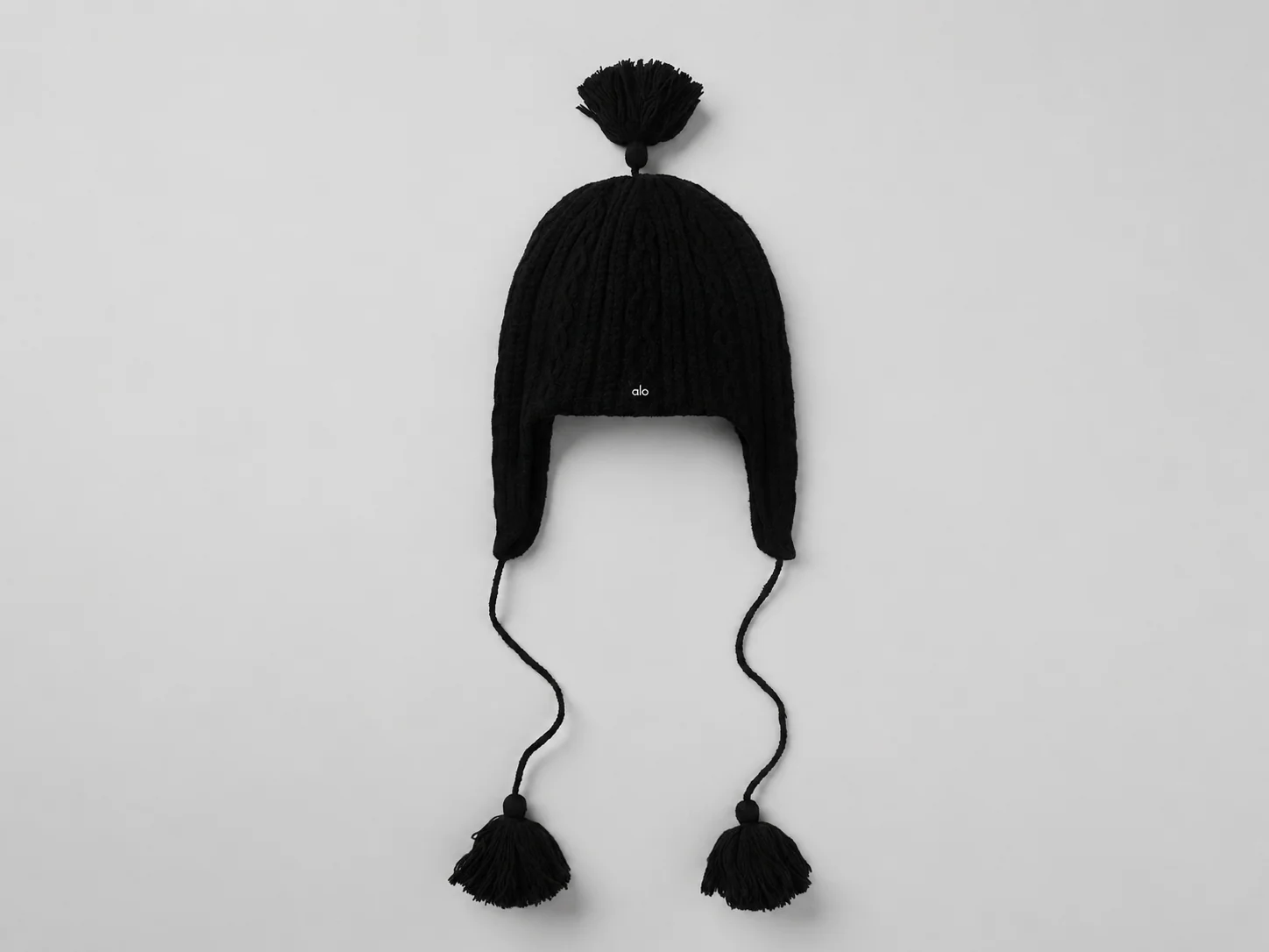 Zopfstrick Winter Bliss Ohrenklappen-Mütze in Schwarz mit übergroßen Quasten